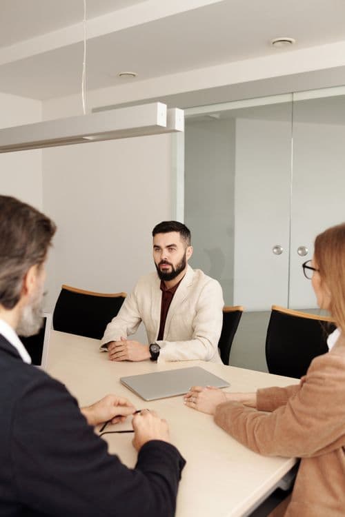 Three professionals discussing work around a meeting table.